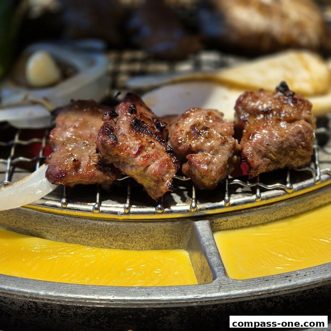 Close-up of grilled meat with onions and garlic on a barbecue grill.