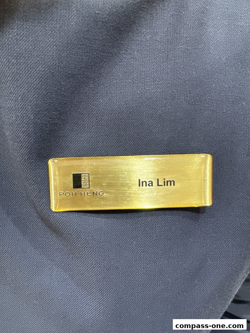 A gold name tag with 'Poh Heng' and 'Ina Lim' engraved on it.
