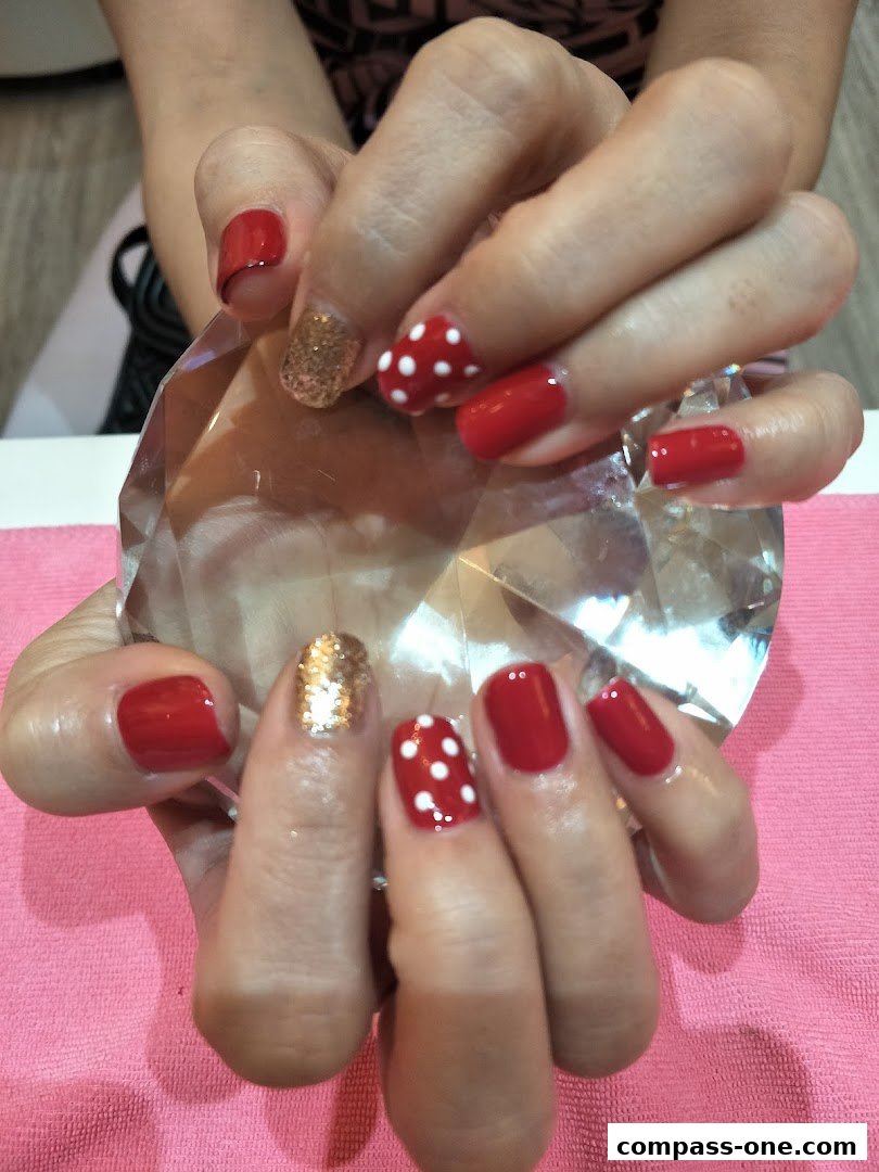 A close-up of hands with red and white polka dot nails and glitter accents.