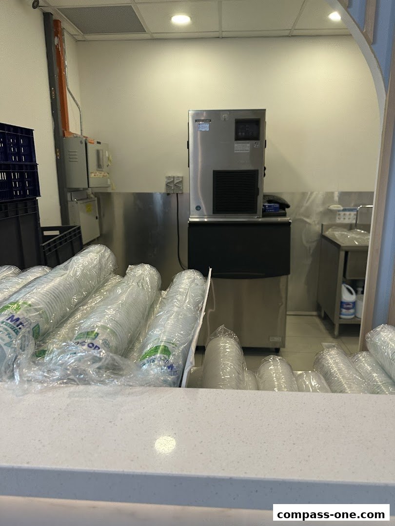 A counter with stacks of plastic cups and an ice machine in the background.