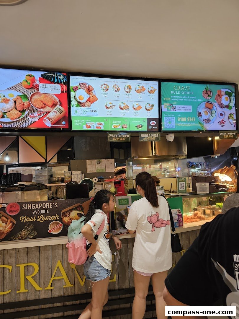 Customers ordering at a Crave Nasi Lemak counter with digital menus displaying food items.