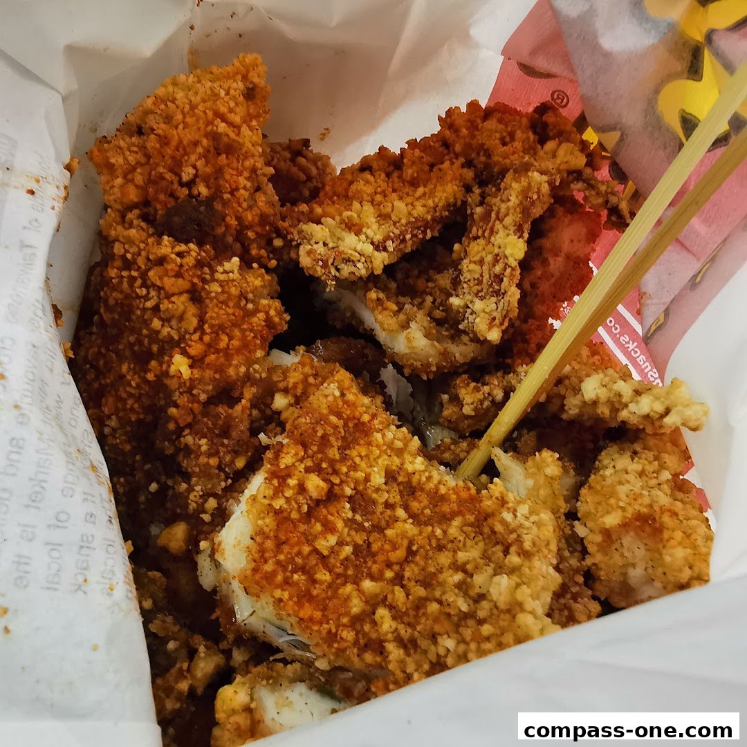 A close-up shot of crispy, golden-brown Taiwanese fried chicken pieces in a paper bag.
