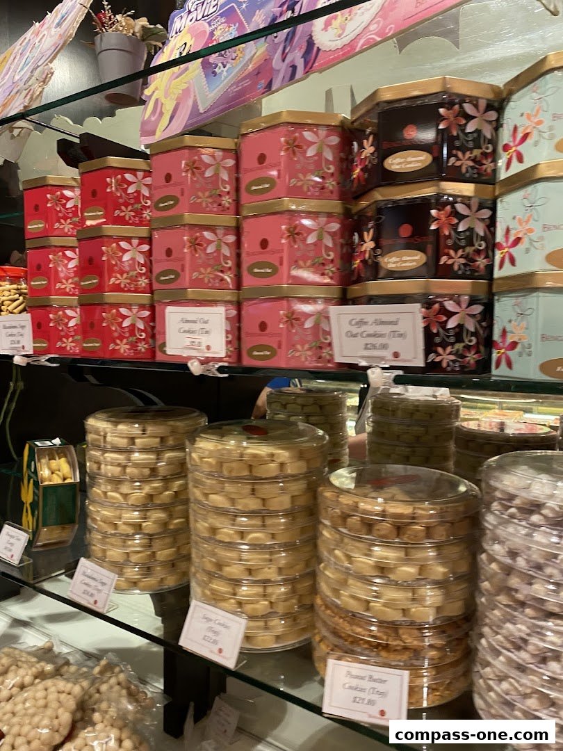 A display of assorted cookies in decorative tins and clear plastic trays.