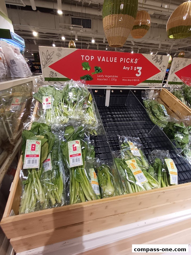 A display of assorted leafy vegetables at a grocery store with a promotional sign.
