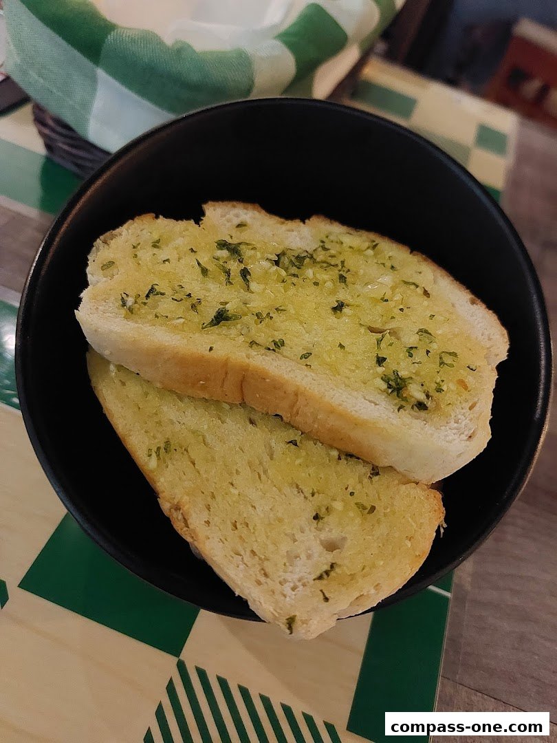 Two slices of garlic bread are served in a black bowl, garnished with herbs.