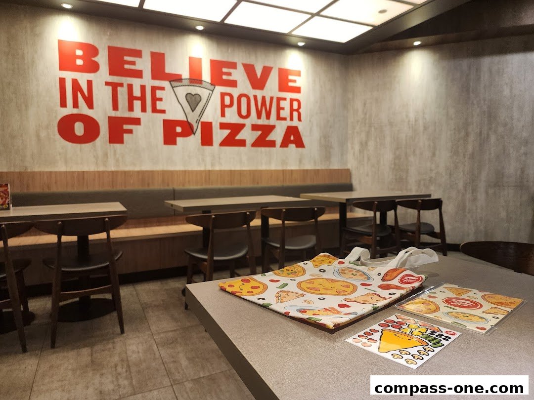Interior of a Pizza Hut restaurant with seating and a wall slogan.