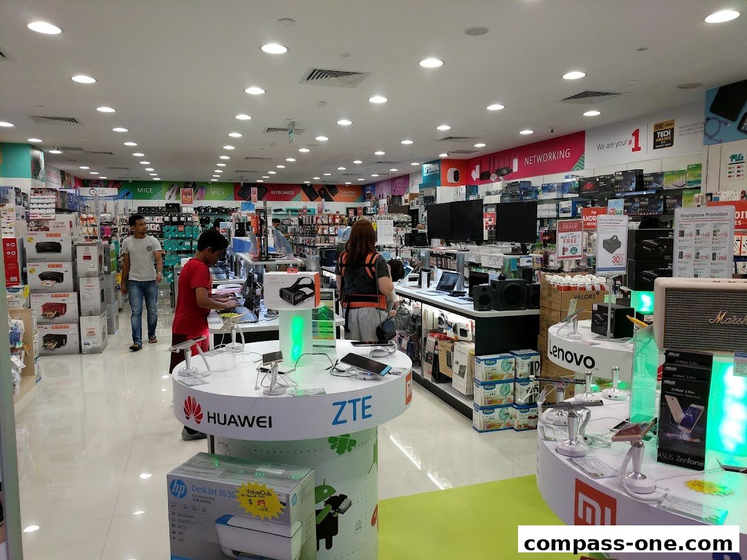 Interior view of a brightly lit electronics store with various products and displays.