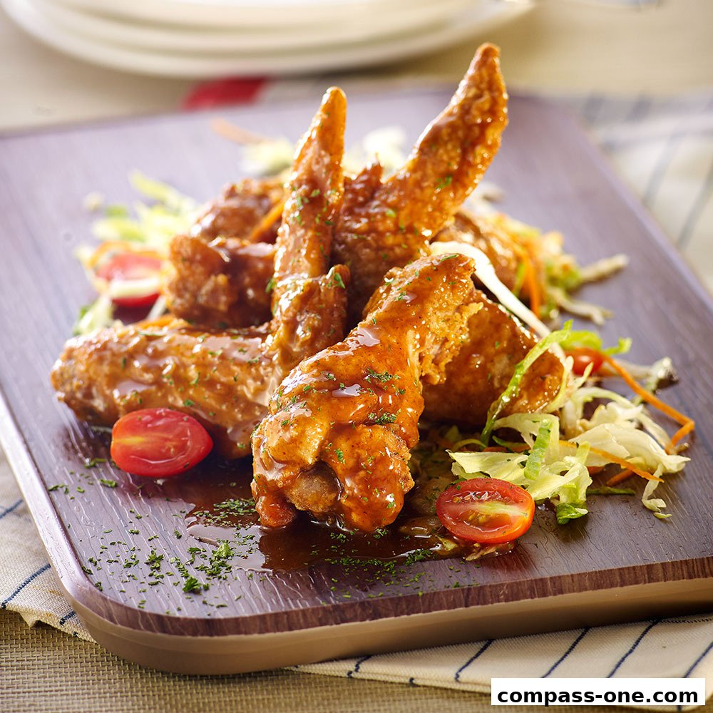 A close-up shot of delicious, glazed chicken wings served with a fresh salad and cherry tomatoes.