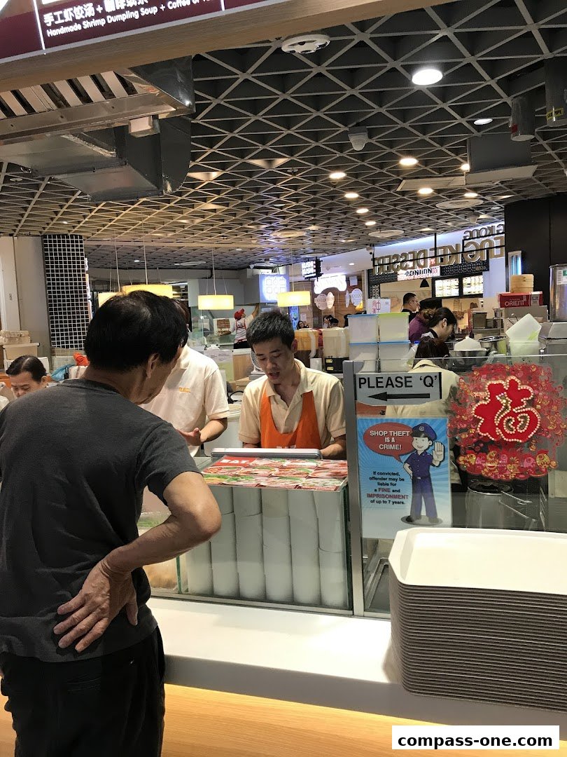 Customers interact with staff at the EAT food counter, with a shop theft warning sign visible.