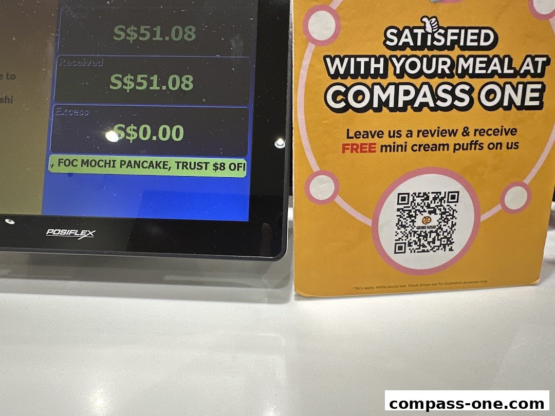 A receipt and a promotional sign for Genki Sushi at Compass One offering free cream puffs.