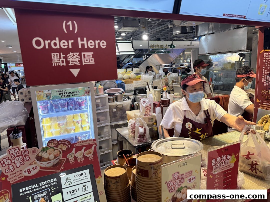 Staff serving customers at Shihlin Taiwan Street Snacks, with food and drinks displayed.