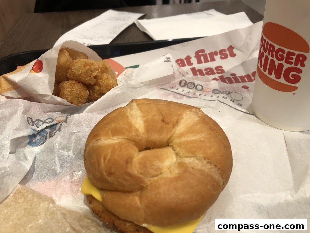 A Burger King meal featuring a croissant sandwich, hash browns, and a drink.