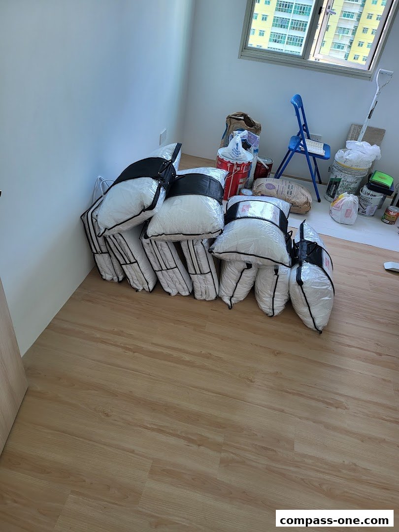 Several white pillows in plastic packaging are neatly stacked on a wooden floor.