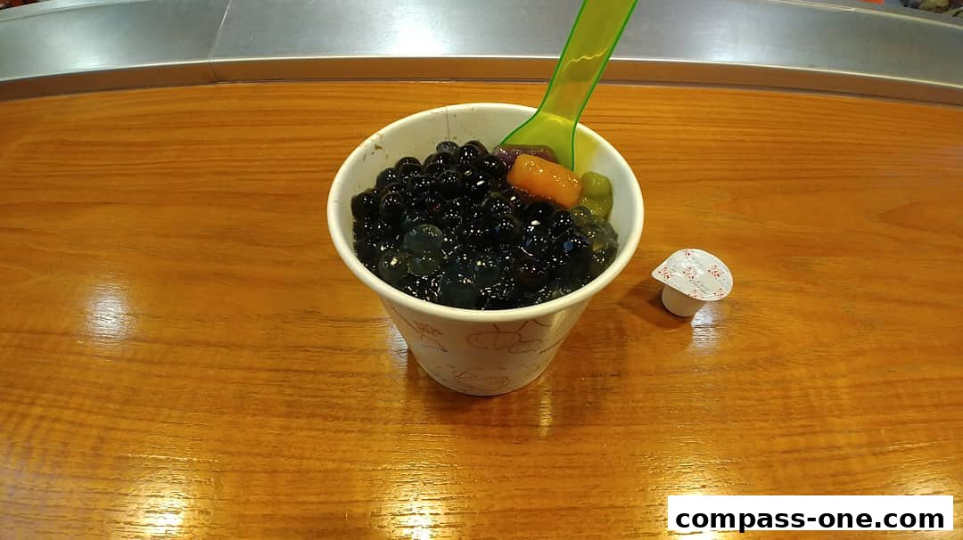 A cup of bubble tea with tapioca pearls and toppings, served with a small packet.