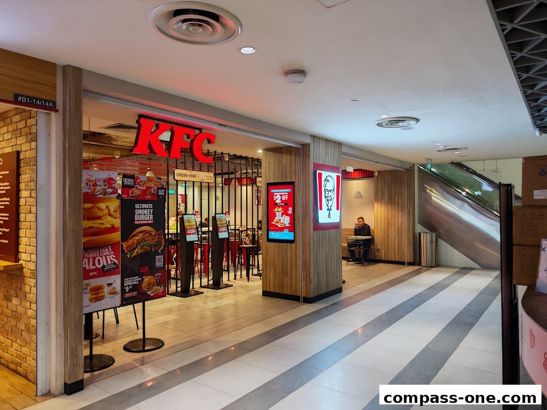 The exterior of a KFC restaurant with promotional posters and an escalator in the background.
