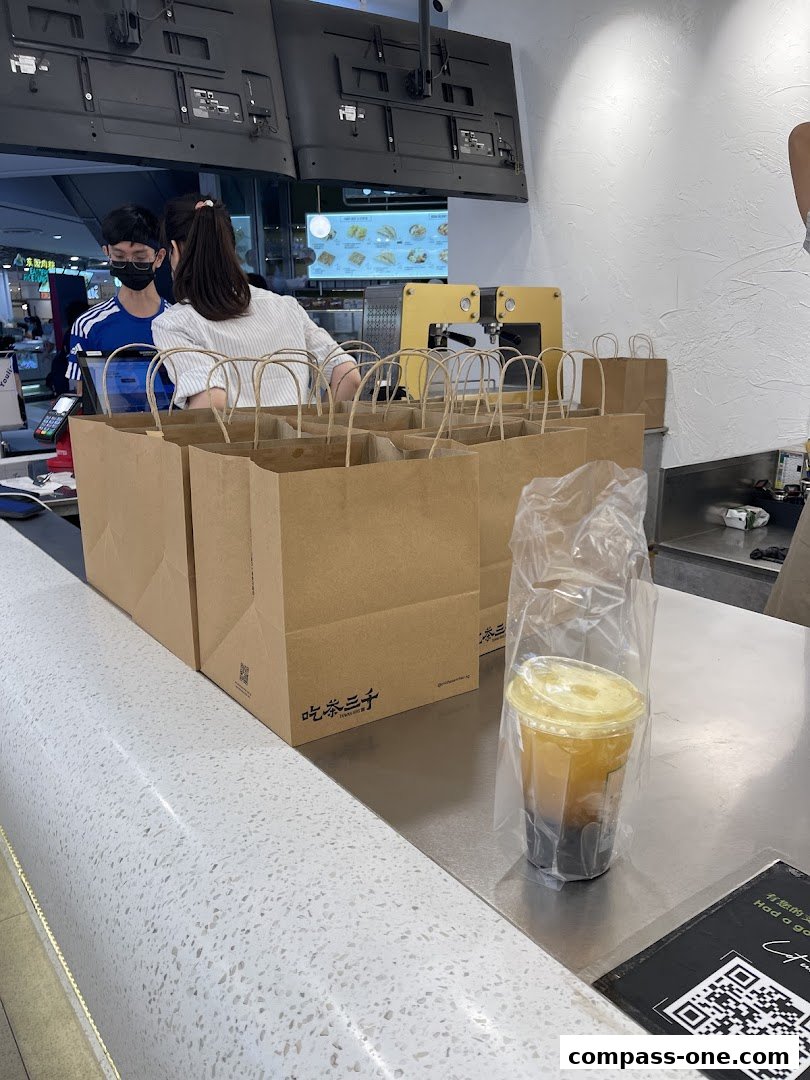 Staff preparing takeaway orders with drinks and paper bags at a counter.