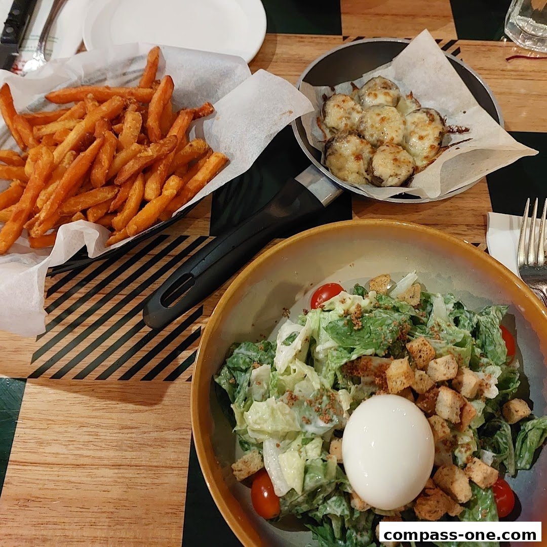 A delicious spread of fries, cheesy mushrooms, and a fresh Caesar salad with a boiled egg.