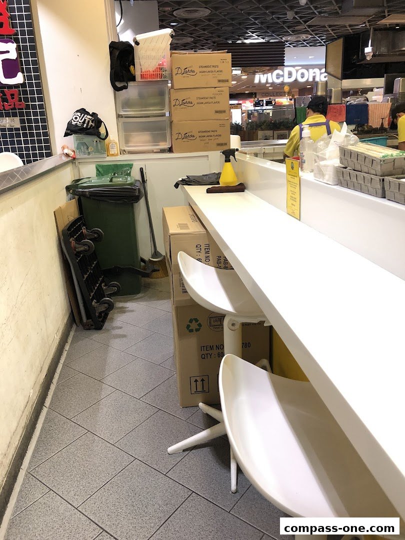 A view of a food stall counter with chairs, boxes, and cleaning supplies.