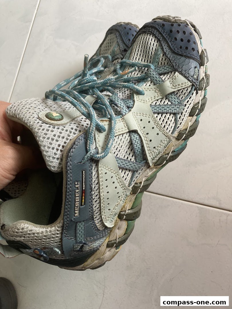 A close-up shot of a worn Merrell hiking shoe with blue laces.