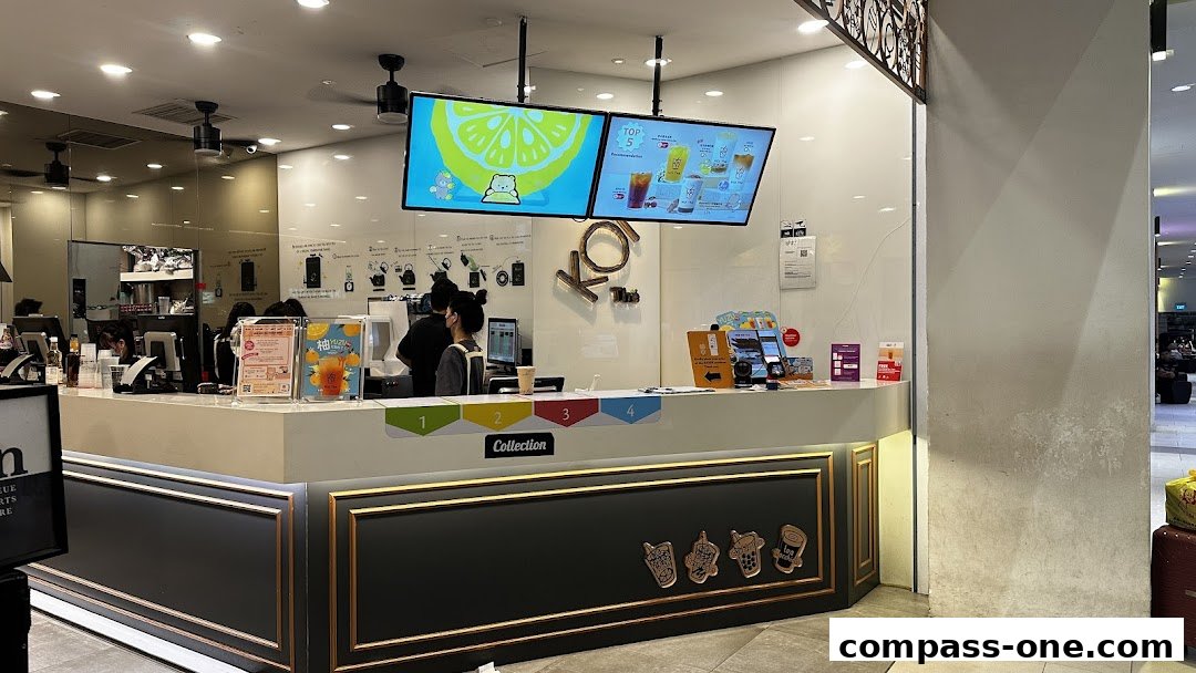 The interior of a KOI Thé bubble tea shop with staff serving customers at the counter.