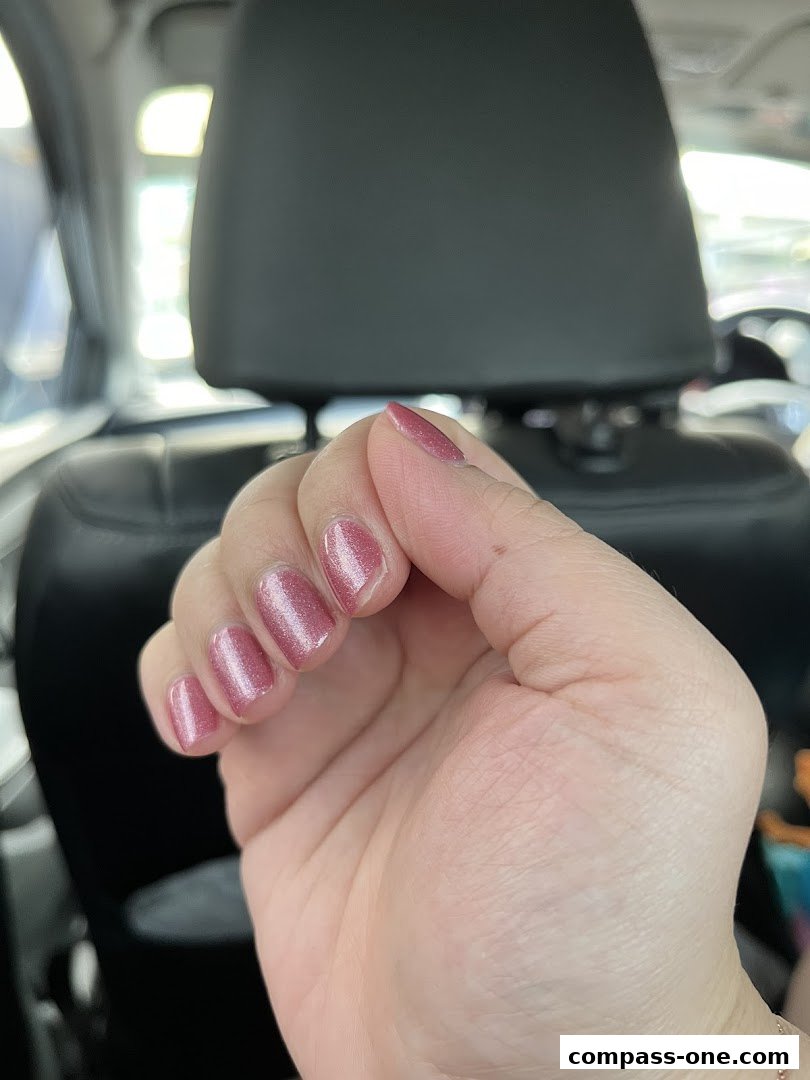A close-up of a hand with freshly painted, shimmering pink nails.
