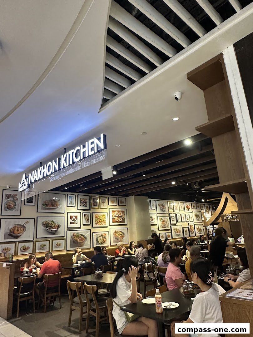 Interior of Nakhon Kitchen restaurant with diners and framed food pictures on the wall.