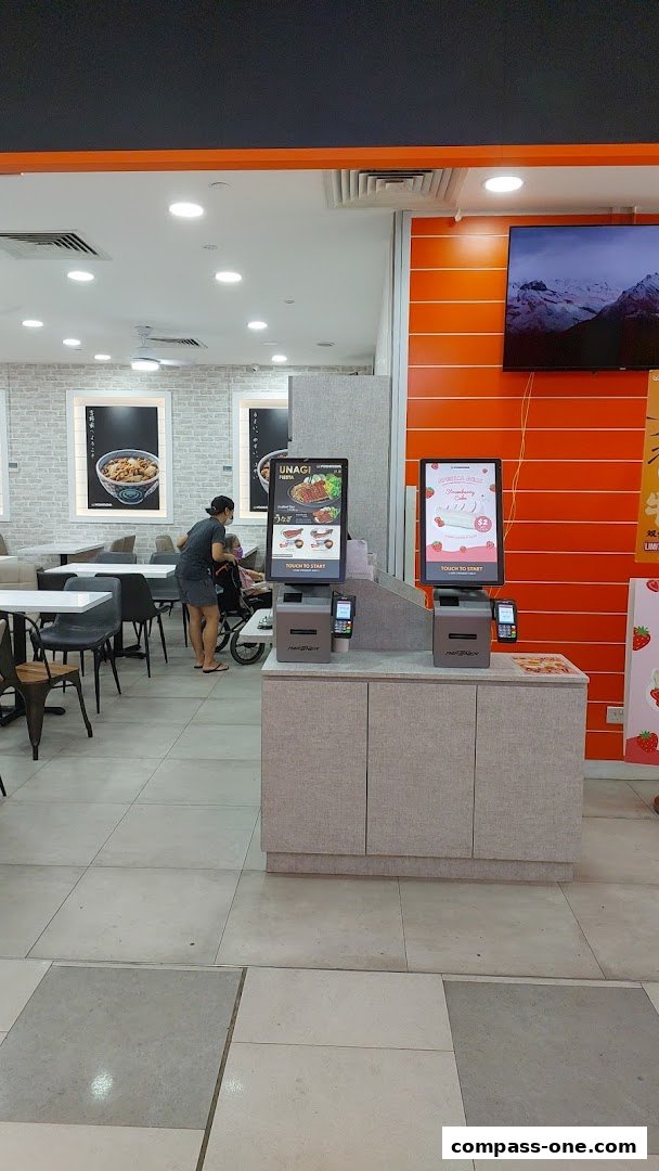 Interior of Yoshinoya with self-order kiosks and dining tables.
