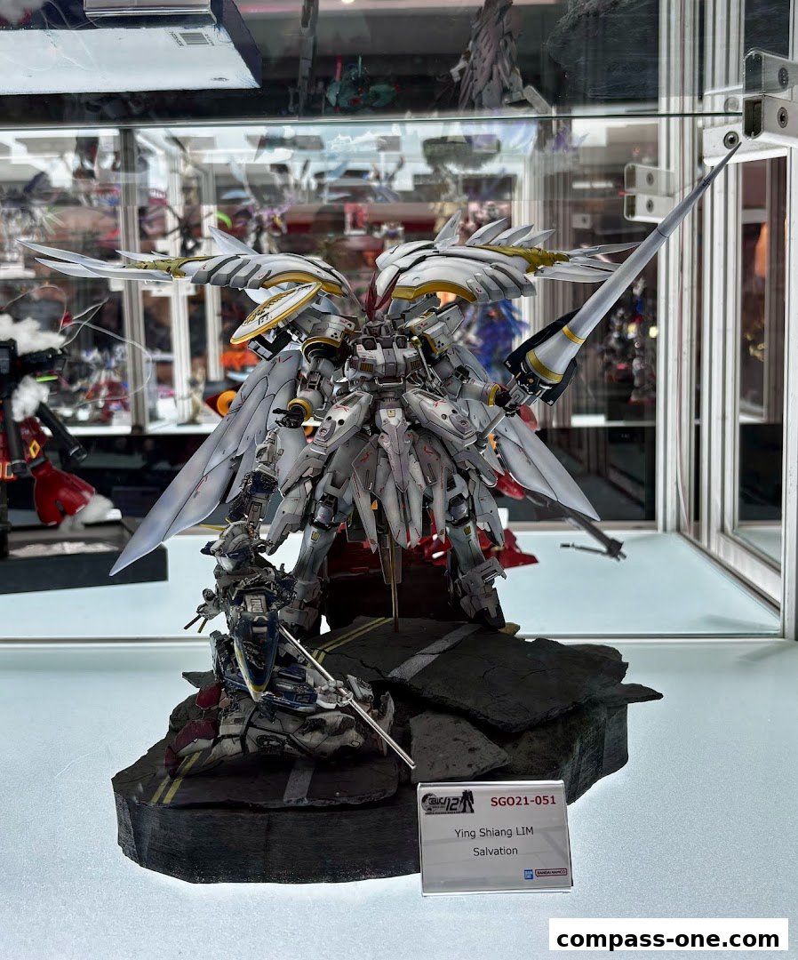 A detailed model of a white and gold mecha with wings, standing on a rocky base.