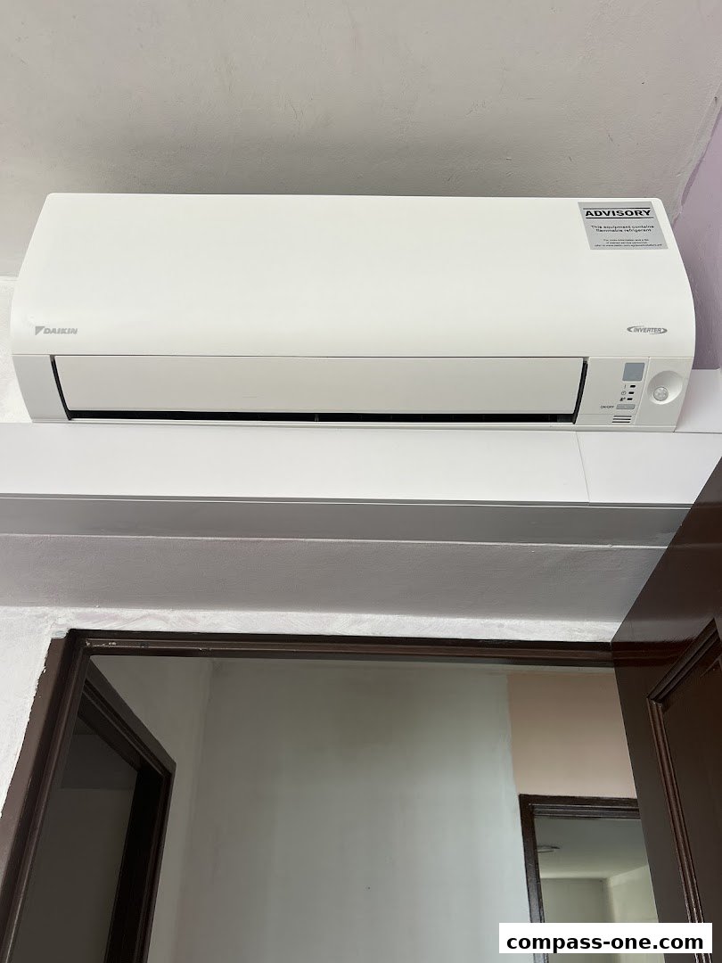 A Daikin inverter air conditioner unit is mounted on a wall above a doorway.