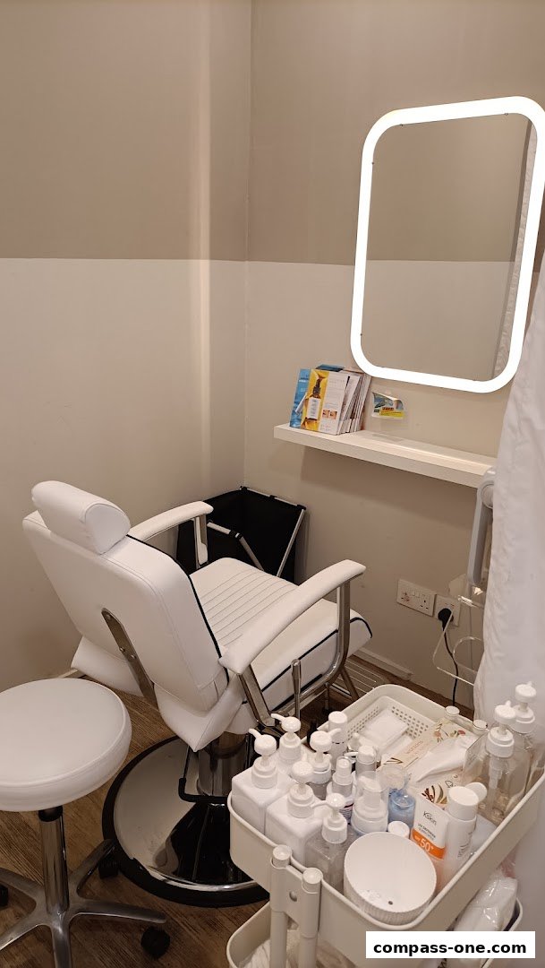 A clean and modern facial treatment room with a white reclining chair and a trolley of skincare products.