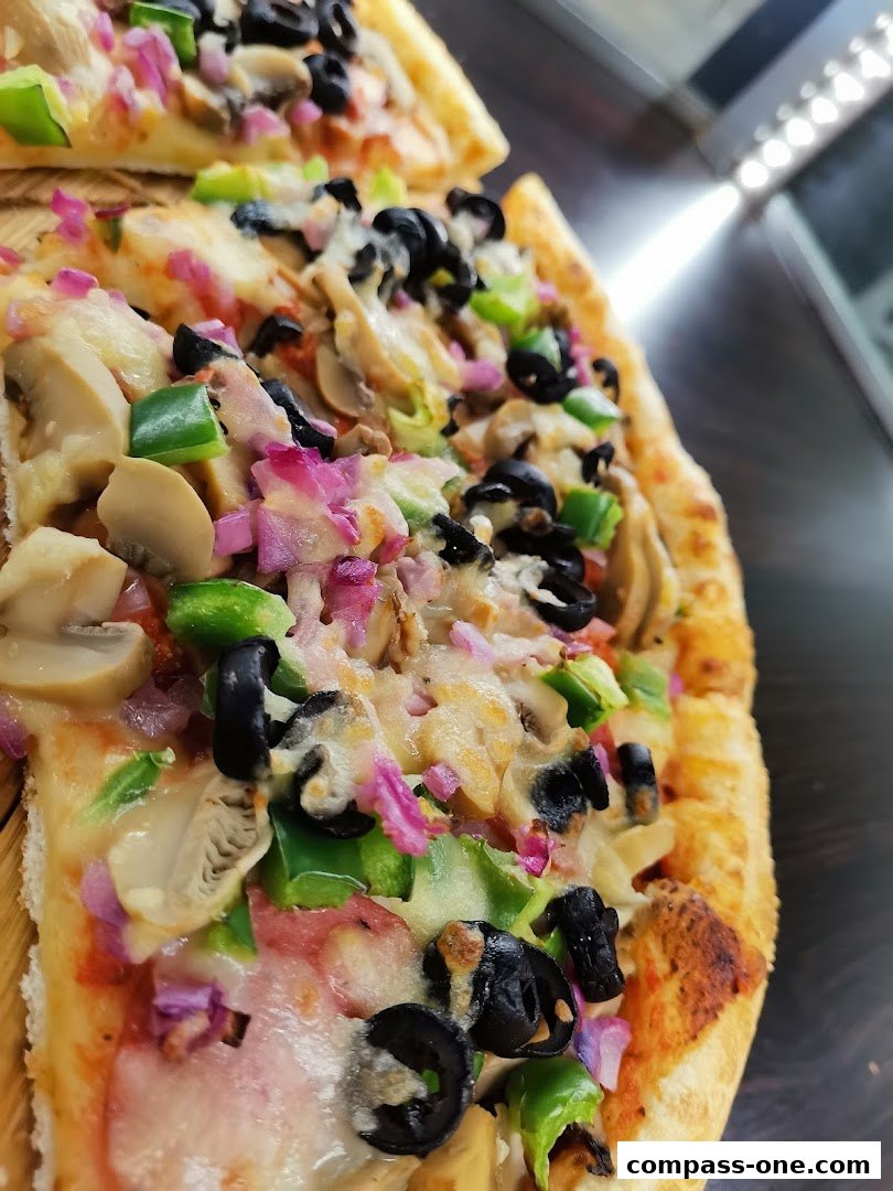 Close-up of two slices of pizza topped with mushrooms, olives, peppers, and onions.