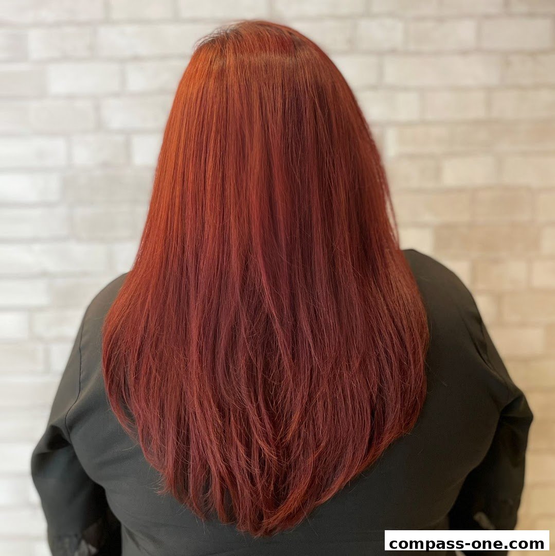 A person's back with long, vibrant red hair styled in layers.