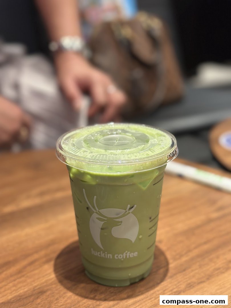 A close-up of a green matcha latte from Luckin Coffee on a wooden table.
