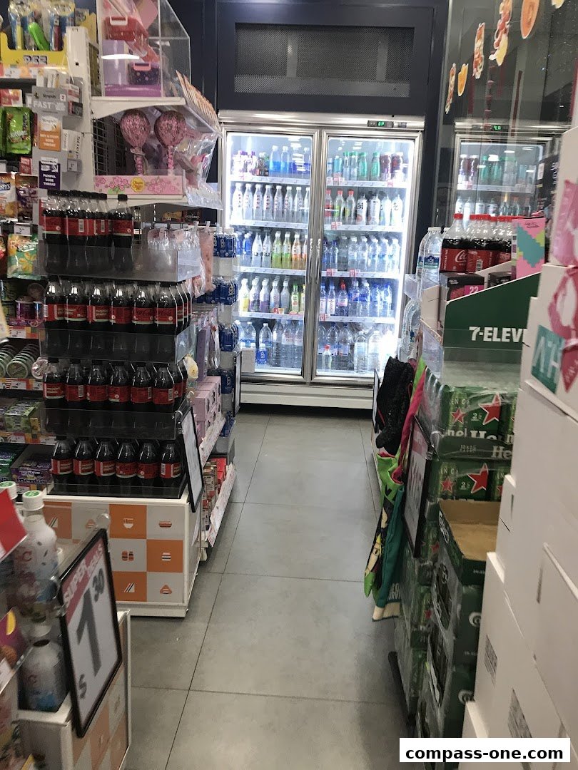 A 7-Eleven store aisle with refrigerated drinks, snacks, and promotional displays.