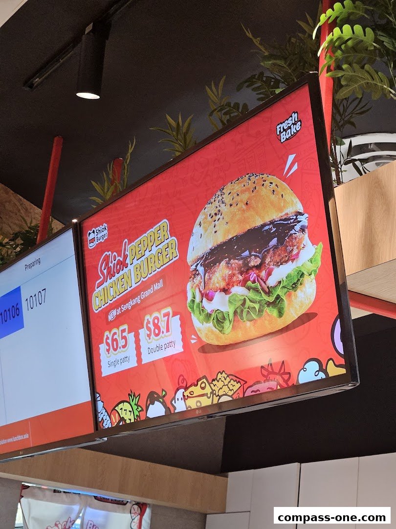 A digital menu board displays a Shiok Burger Pepper Chicken Burger with prices.