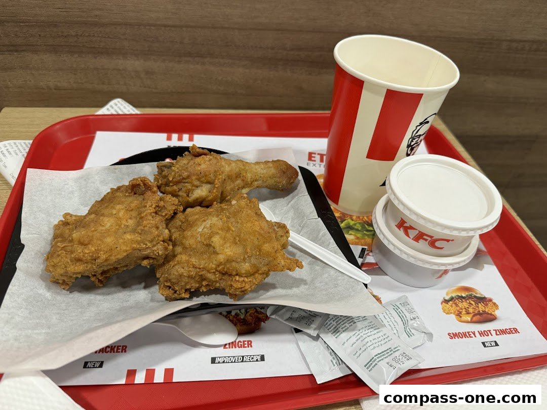 A tray of KFC fried chicken, a drink cup, and dipping sauces.