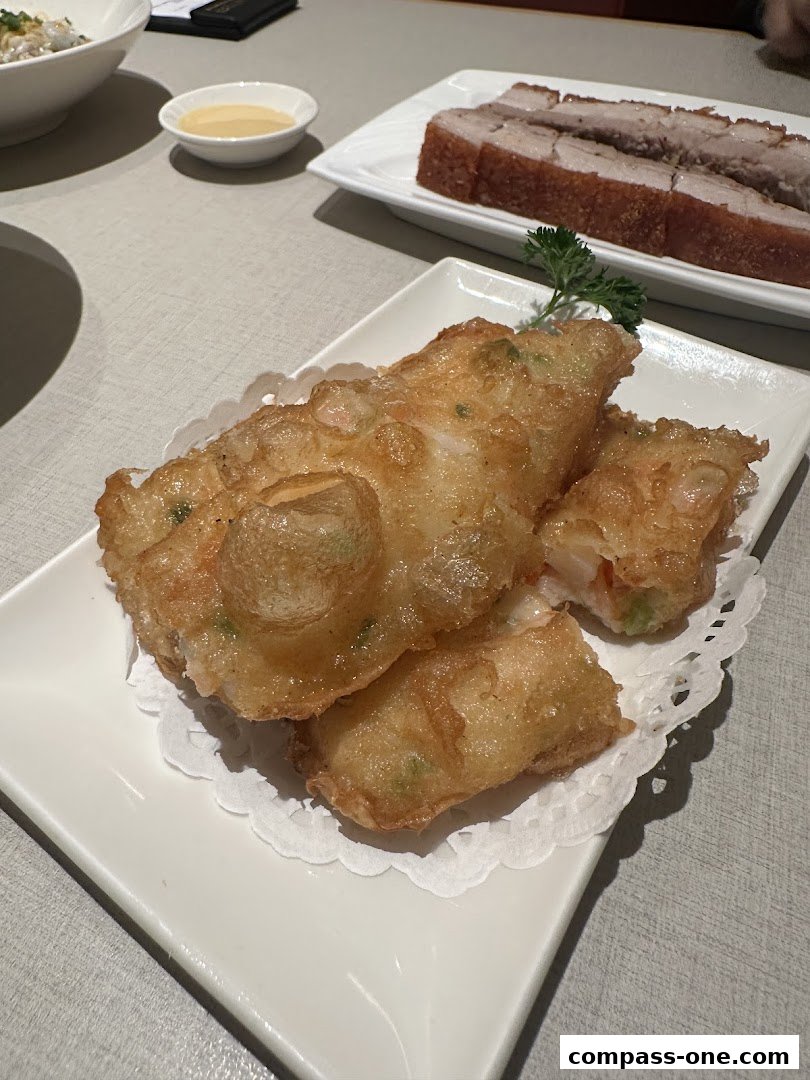 Crispy fried shrimp rolls and roasted pork belly served on white plates.