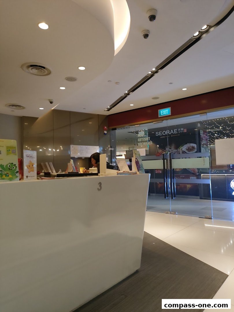 A reception desk with a staff member and promotional materials inside a brightly lit establishment.