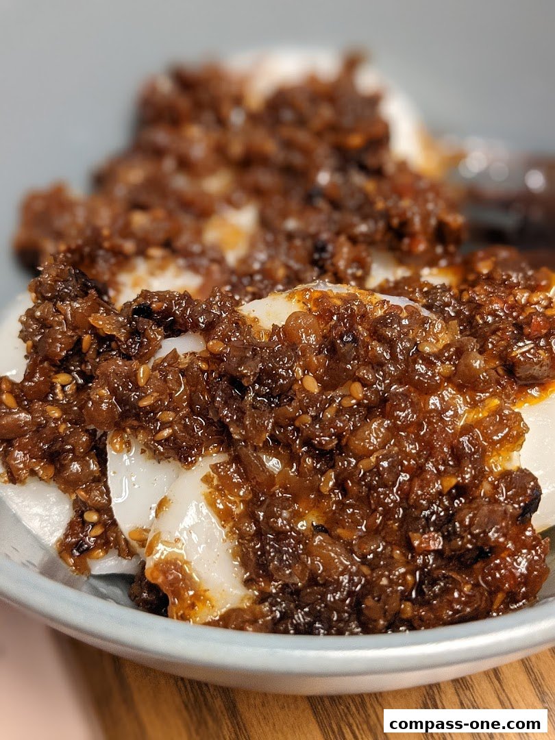 A close-up of Jian Bo Shui Kueh, a traditional snack with white jelly-like cakes topped with savory minced ingredients.
