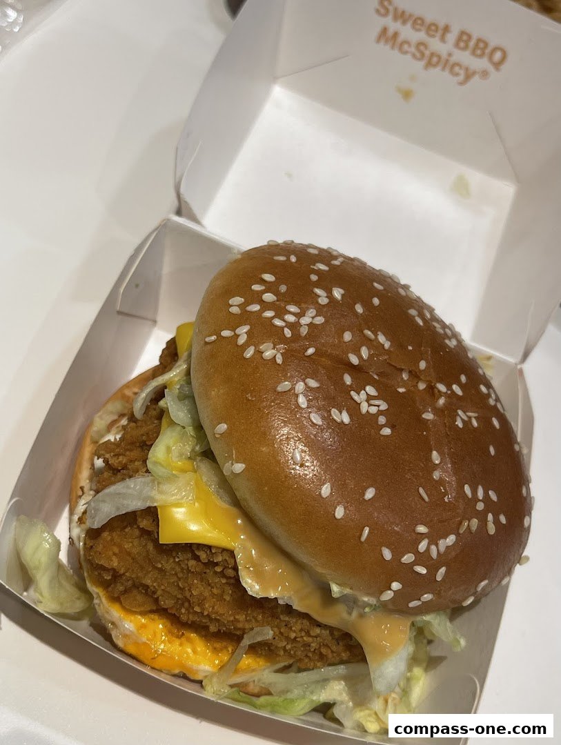 A close-up of a McSpicy burger in its packaging, featuring a sesame seed bun and crispy chicken.