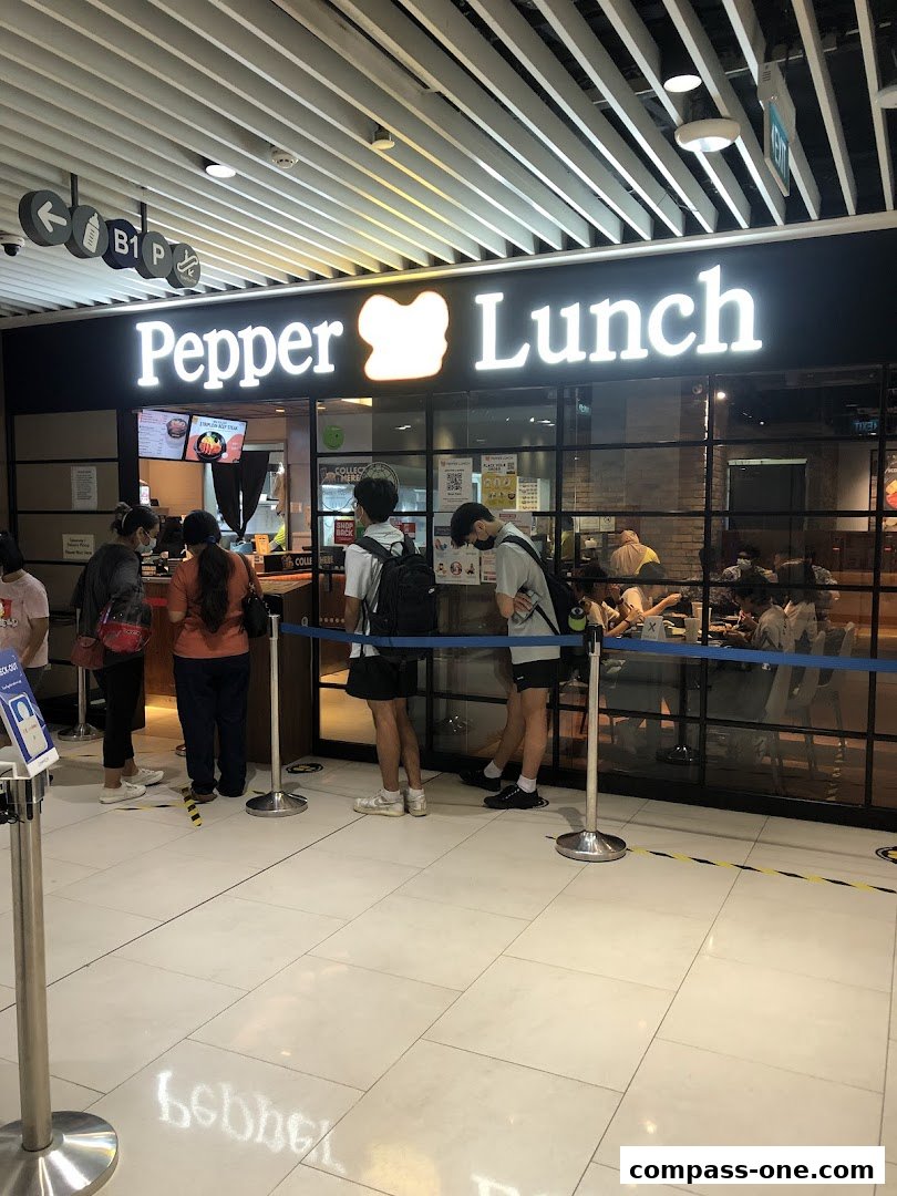 People queuing outside the Pepper Lunch restaurant with its illuminated sign.