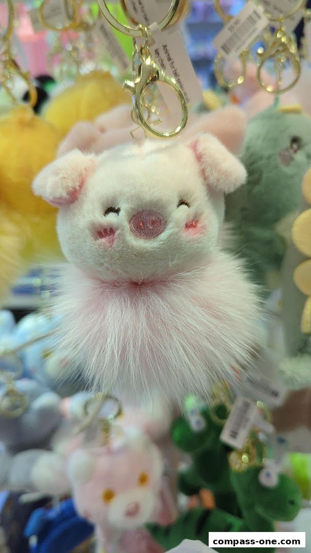 A close-up of a fluffy pink pig keychain with a fluffy collar.