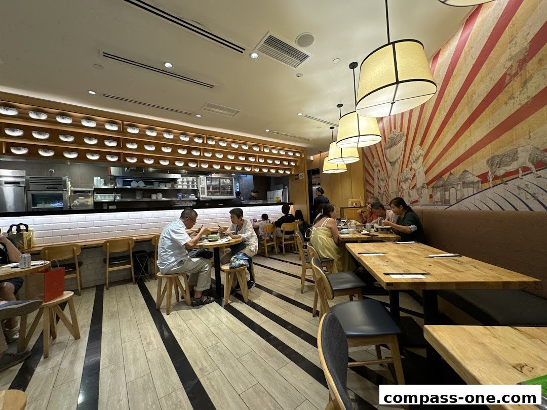 Diners enjoy a meal inside LeNu Chefs Wai Noodle Bar, with a view of the kitchen and unique decor.