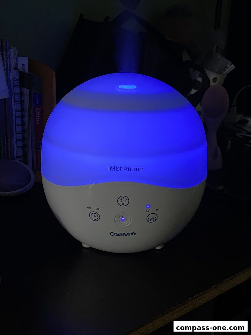 An OSIM uMist Aroma diffuser emitting blue mist and light.