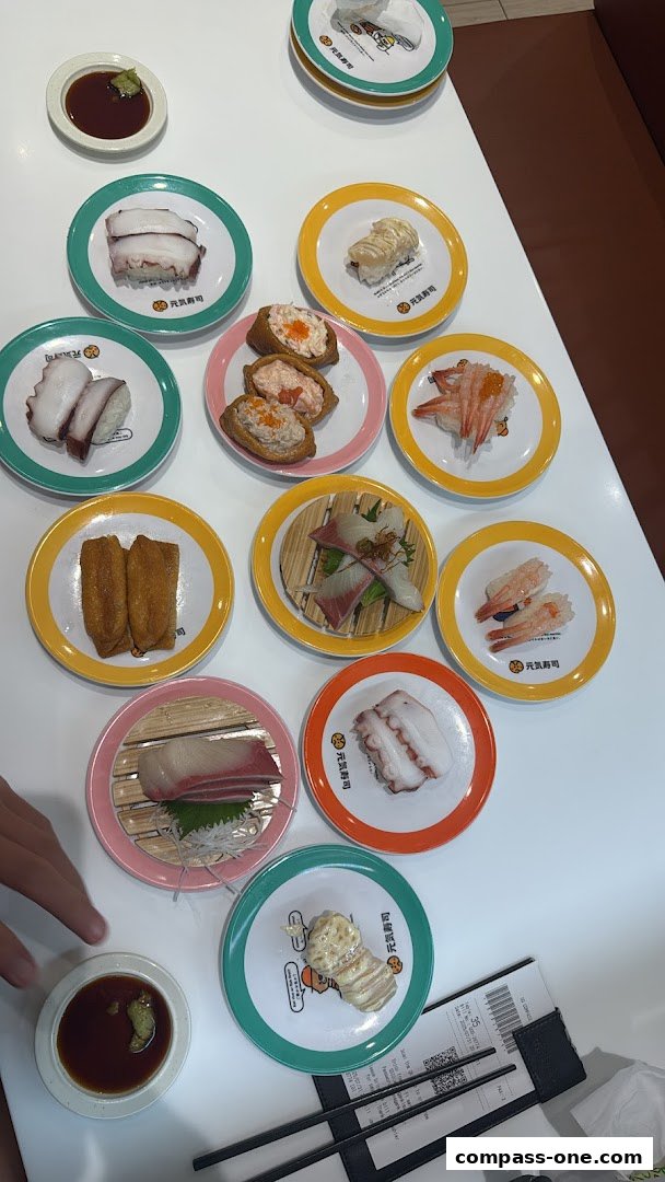 A table full of colorful plates of sushi and dipping sauce.