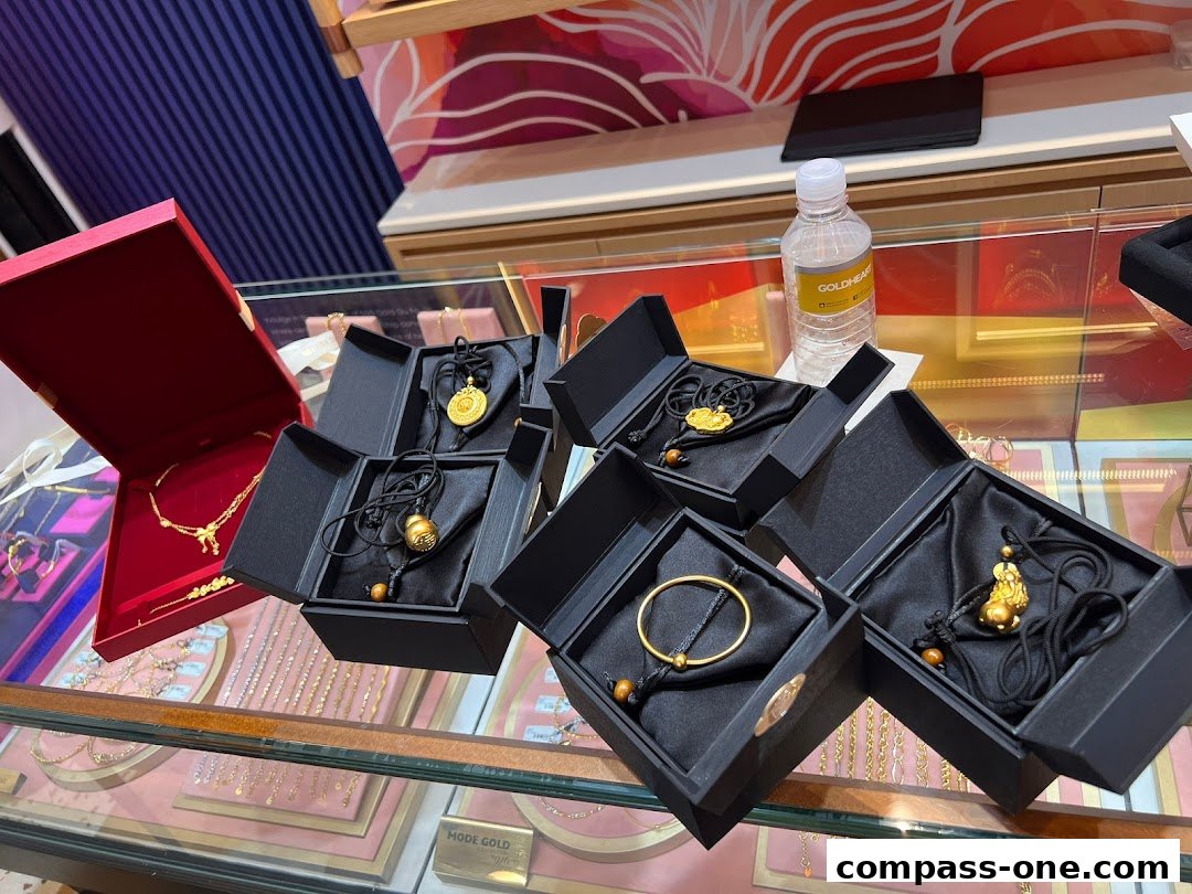 Gold jewelry displayed in black boxes and a red case, with a bottle of water in the background.