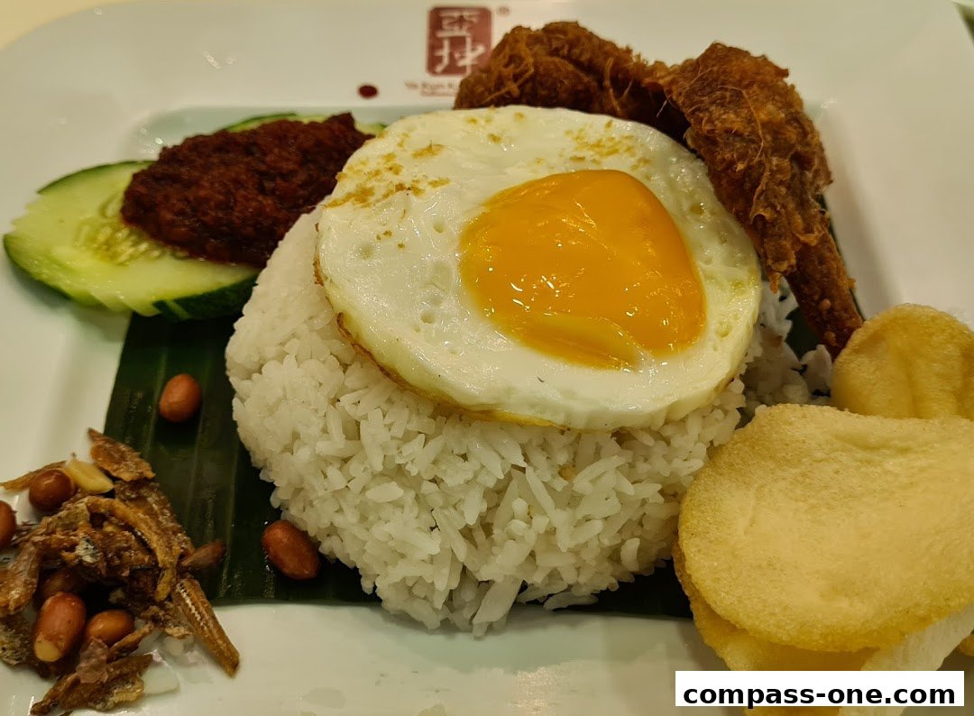 A plate of Nasi Lemak with fried chicken, sunny-side-up egg, and various accompaniments.