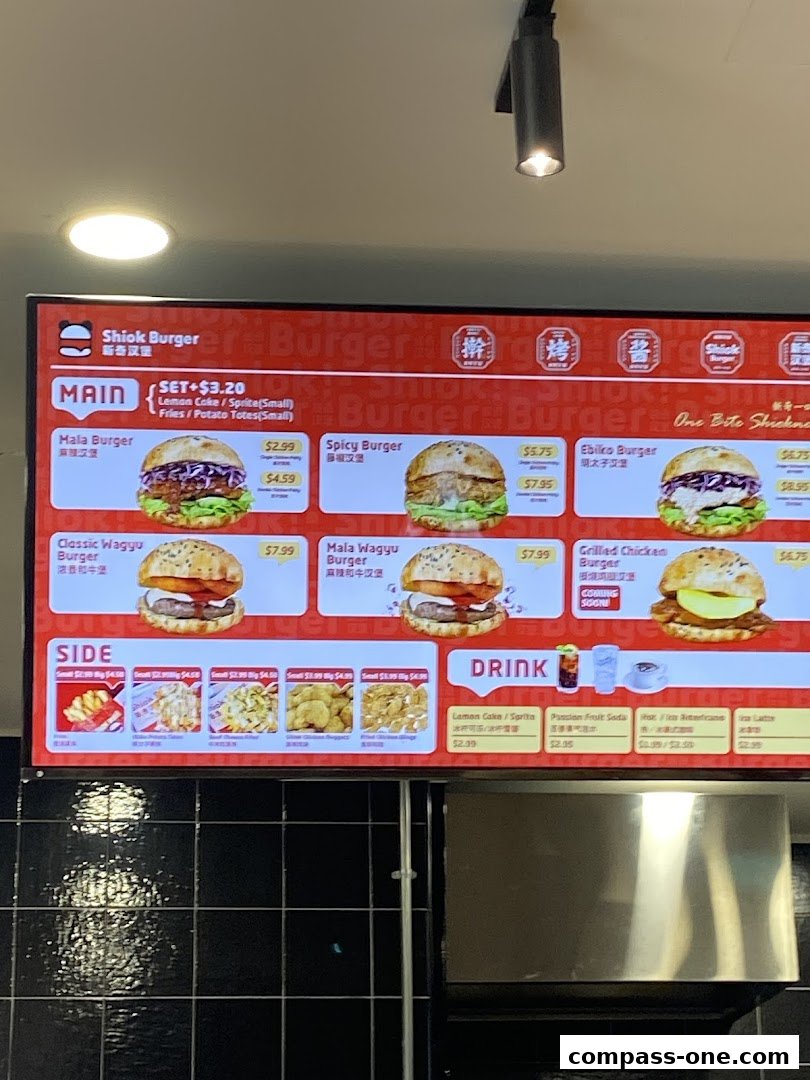 A digital menu board displaying various burgers, sides, and drinks from Shiok Burger.
