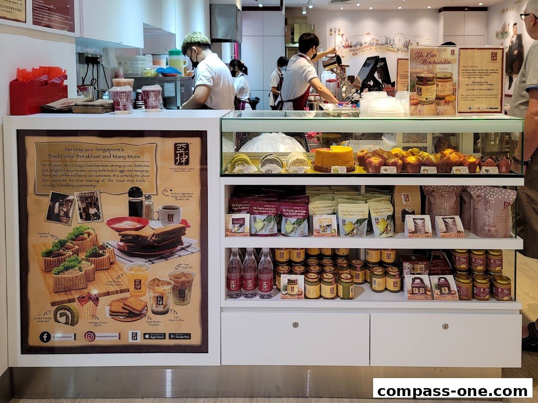 A display counter at Ya Kun Kaya Toast featuring baked goods, packaged merchandise, and promotional materials.