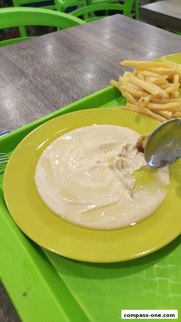 A plate of hummus with olive oil and a side of french fries, served on a green tray.